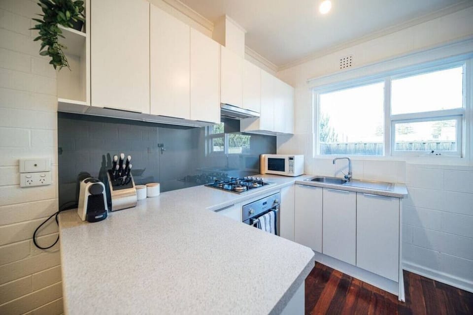 Bright, modern kitchen with gas cooktop, coffee machine, and plenty of natural light, fully equipped for easy everyday cooking.