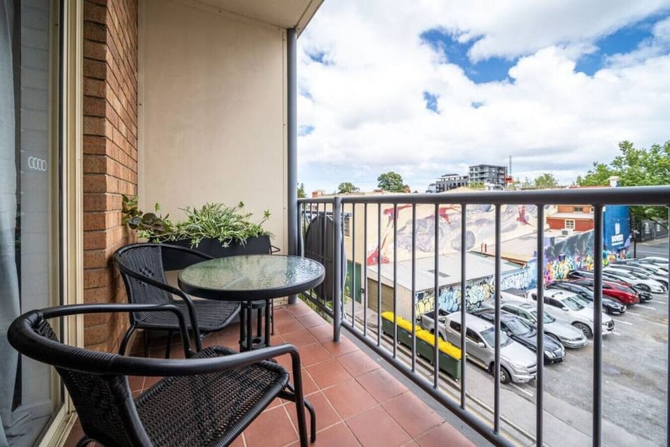 A private balcony with bistro seating offers a peaceful spot for morning coffee or fresh air overlooking the courtyard below.