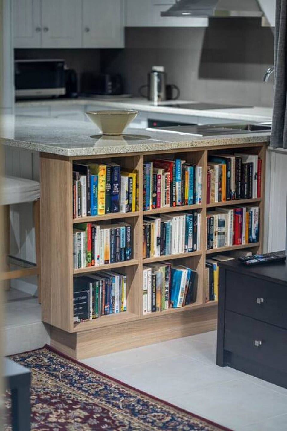 A well-stocked bookshelf built into the kitchen island adds character and a touch of charm to the space.