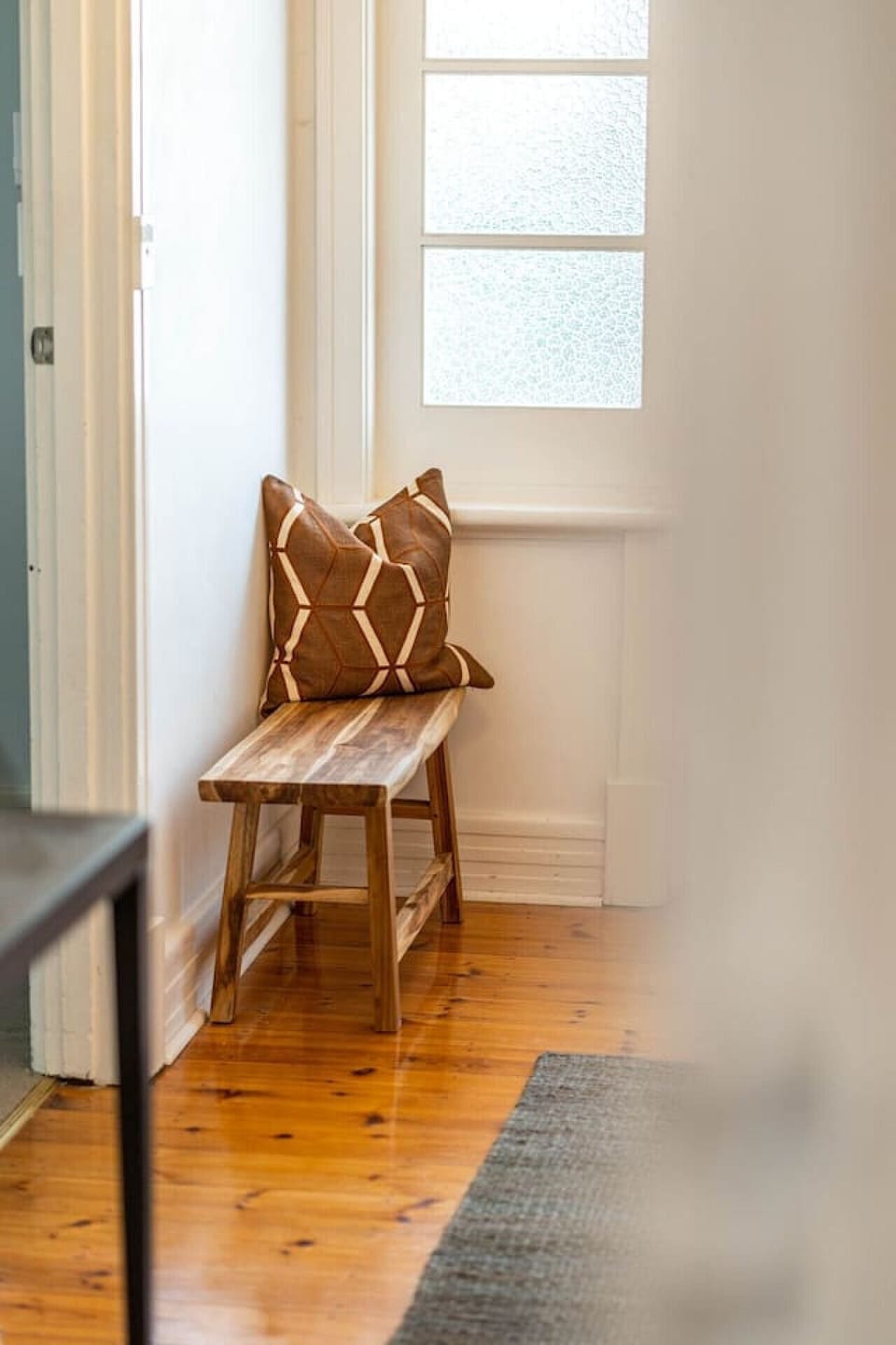 A simple wooden bench adds charm to the sunlit entryway.