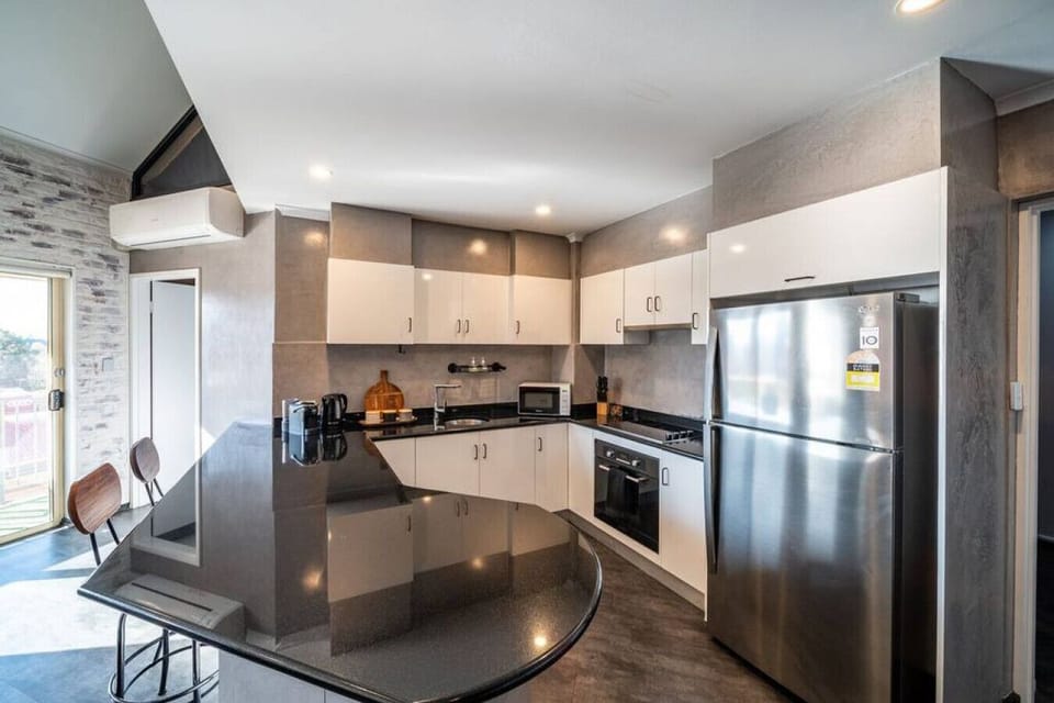 Prepare meals with ease using modern appliances, including a full-sized fridge, oven, cooktop and Nespresso machine, all set within a sleek, functional layout.