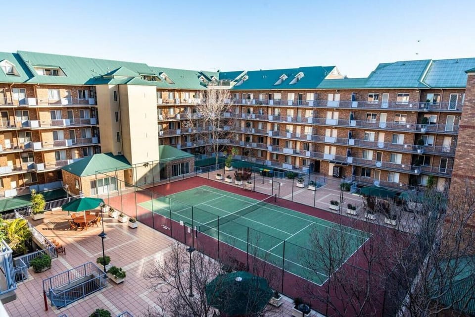 The shared courtyard features a full-sized tennis court surrounded by the character-filled architecture of the complex.