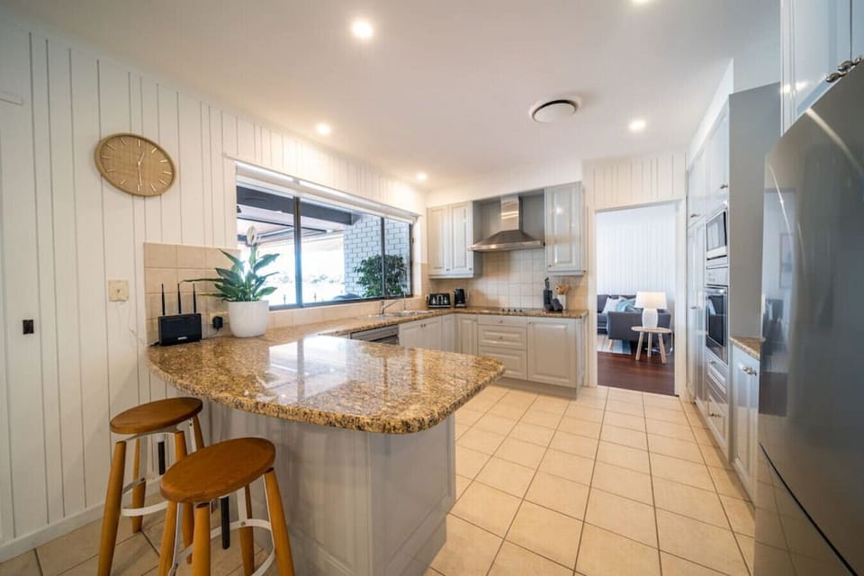 A spacious, light-filled kitchen with stone benchtops and a breakfast bar makes mornings easy, whether you’re preparing a quick coffee or settling in for a slow start to the day.