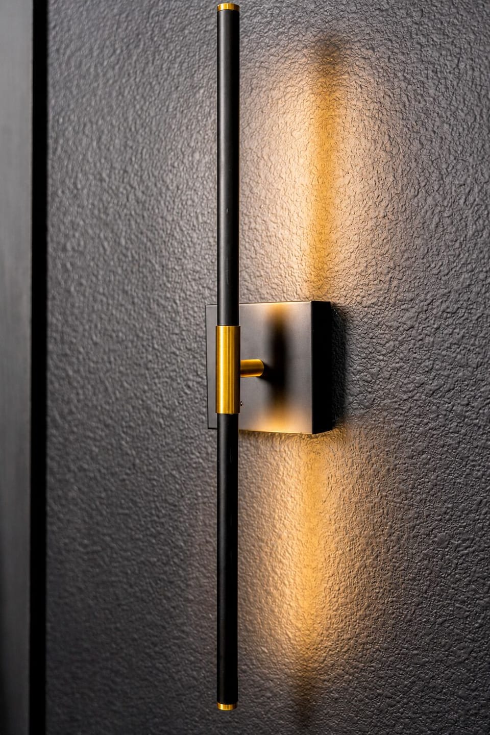 Modern black-and-brass wall sconce with warm ambient glow
