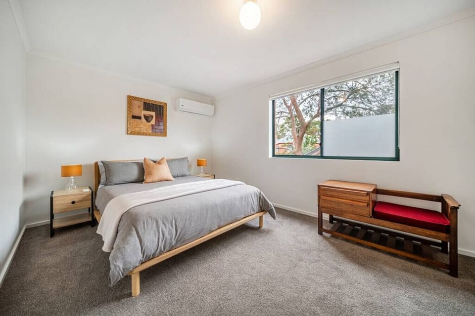 Wake to gentle morning light in the primary bedroom, featuring a queen bed, built-in storage, and split-system comfort.