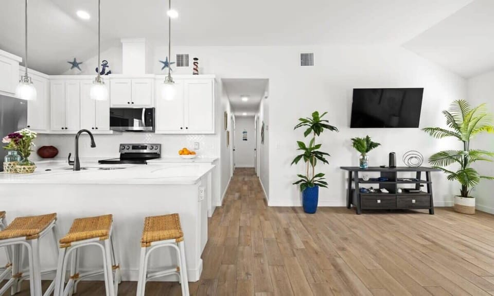 Kitchen & Living — White Island, Wicker Bar Stools, Hallway to Bedrooms & Wall TV