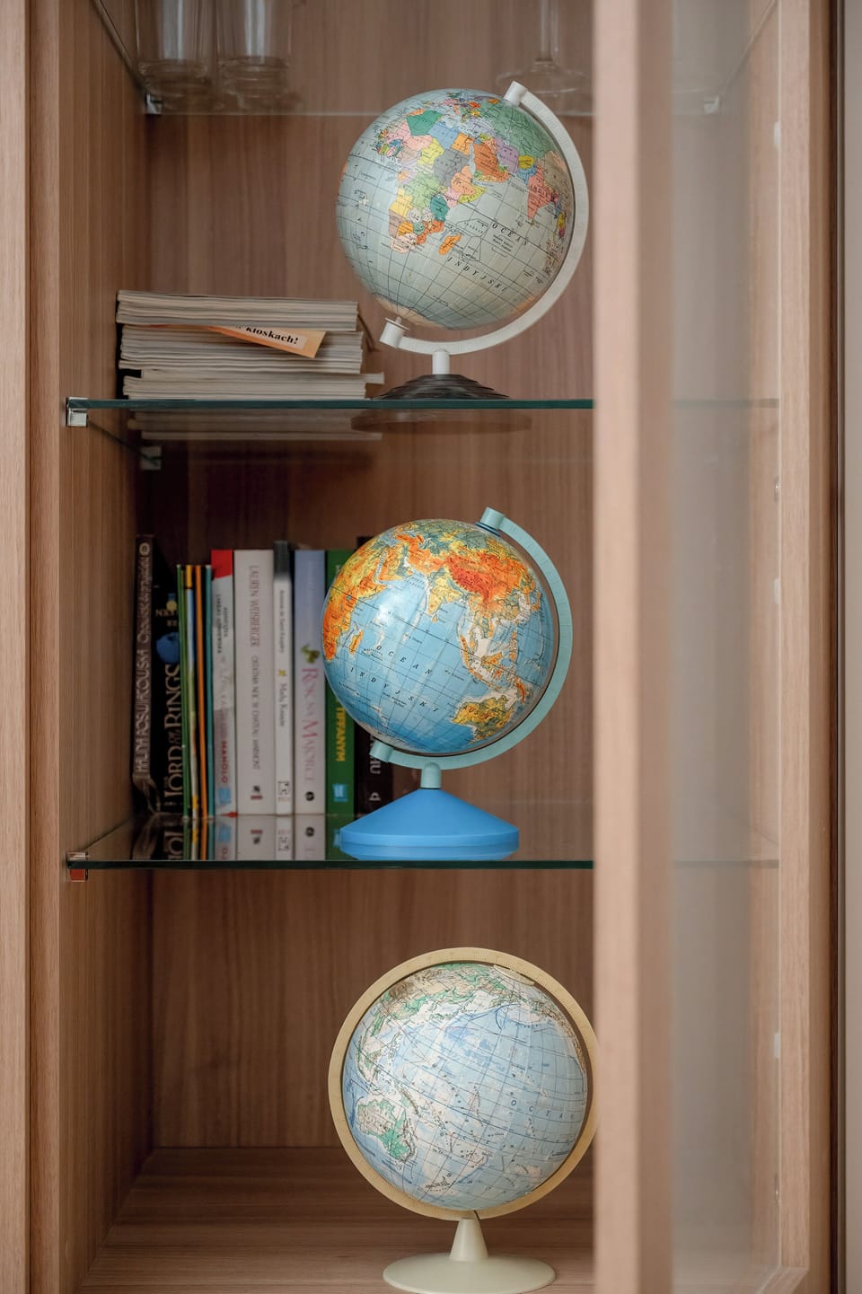 A close-up of a wooden bookshelf with a decorative globe collection.