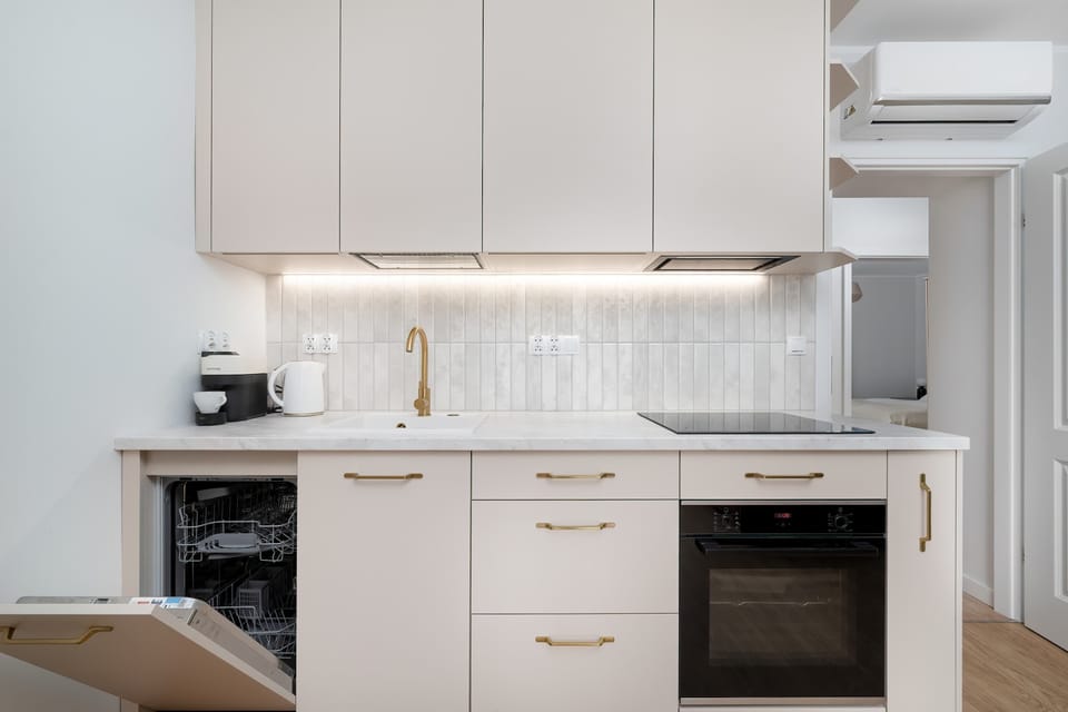 A compact kitchen with modern appliances, cream cabinetry, and soft lighting.
