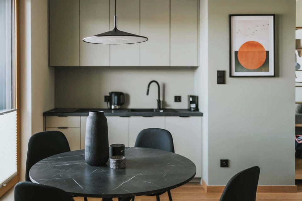 Open-plan living space with a dining area and kitchenette. Modern furniture and light decor make the room feel spacious.