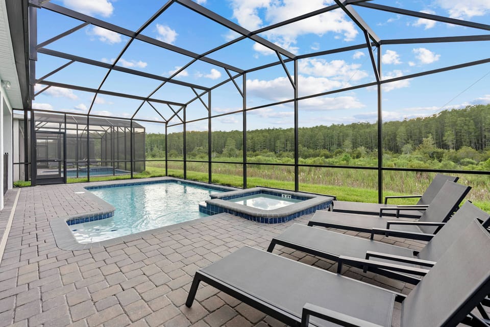 Step outside to your private oasis with a sparkling pool and soothing spa, surrounded by a spacious deck and sleek lounge chairs. Enjoy breathtaking views of lush greenery while soaking up the sun in your serene retreat.