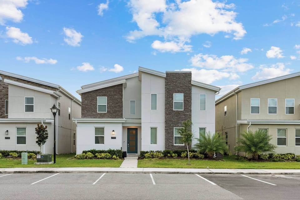 Step into a stylish exterior featuring a striking combination of light and dark siding, framed by lush greenery. The inviting path leads to a well-lit entrance, creating a welcoming first impression for your stay.