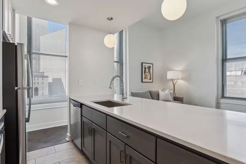 Prep meals beside sunny windows on expansive quartz counters.