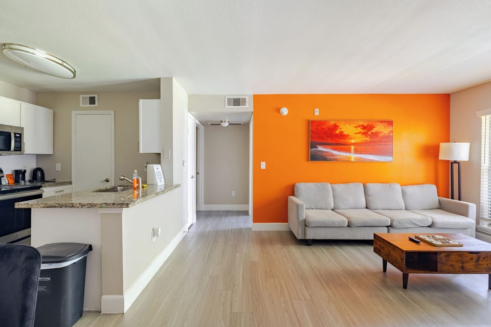 Bright open living room with bold accent wall and granite breakfast bar
