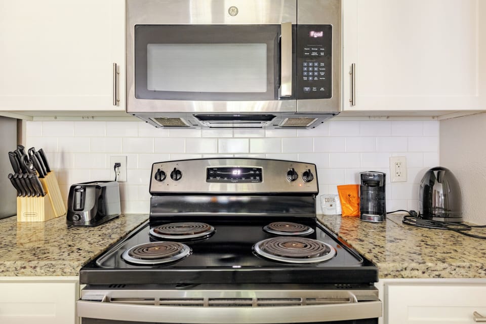 Modern kitchen with stainless appliances, granite counters, and coffee setup