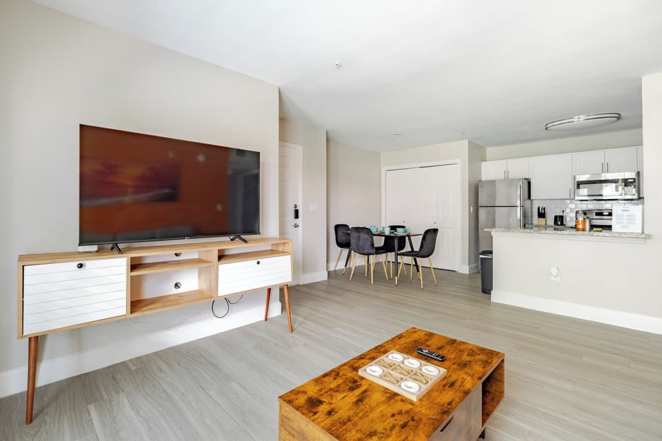 Bright open-concept living space with TV, dining nook, and modern kitchen
