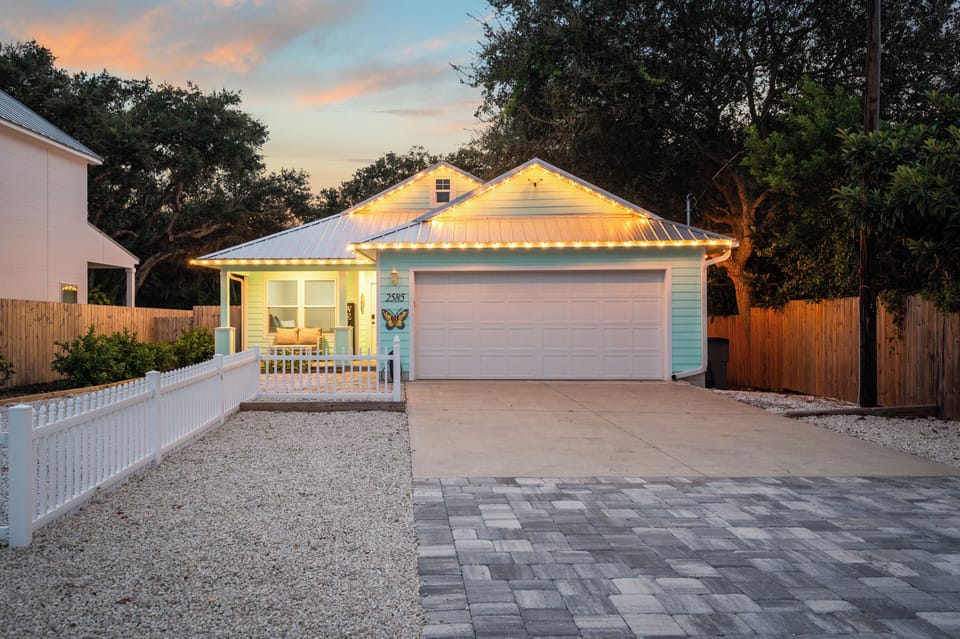 Welcoming coastal-style with charming front porch and lights.