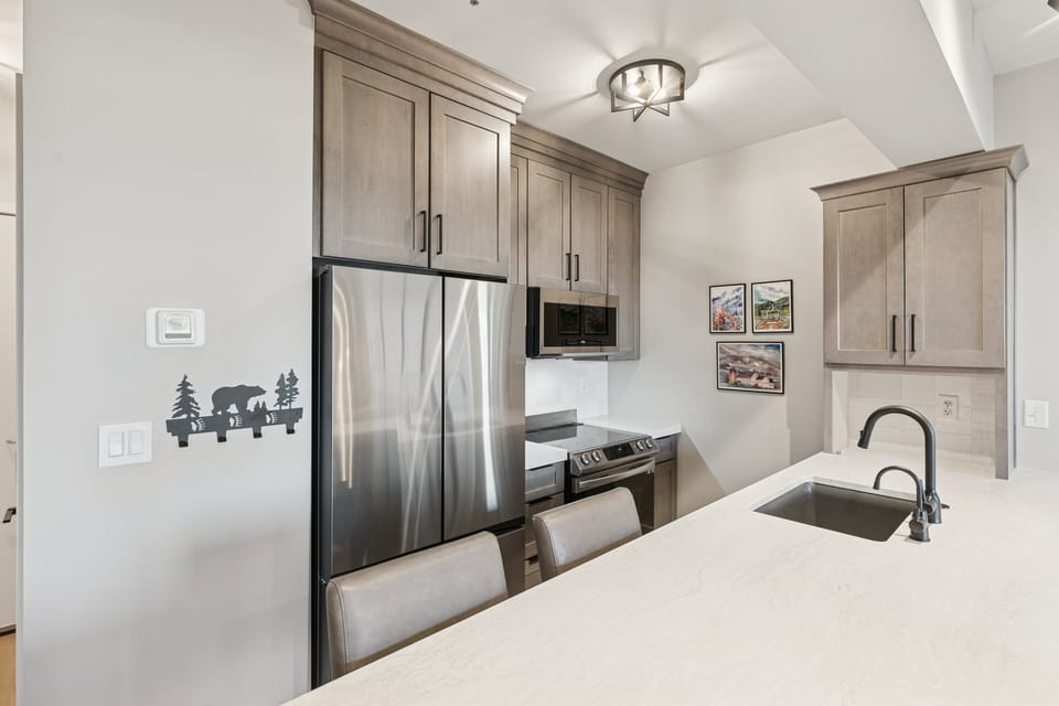 Modern condo kitchen with stainless steel appliances, quartz countertops, and wood cabinetry.