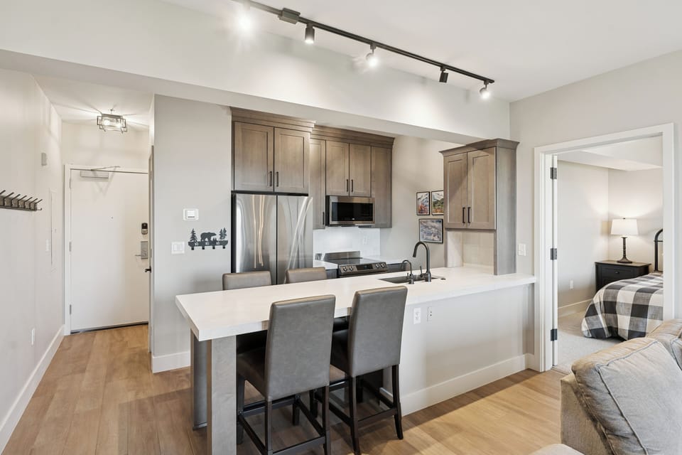 Open-concept kitchen and dining area in a Park City condo, featuring wood finishes and upscale appliances.