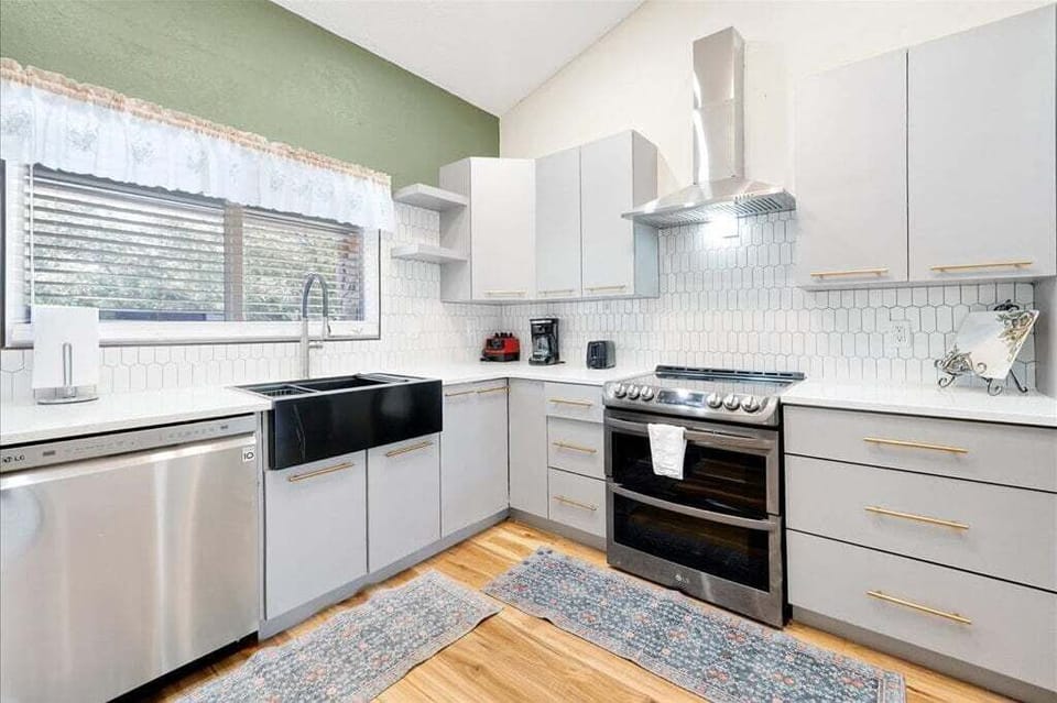 A spacious, fully-equipped kitchen featuring sleek white cabinetry, gold hardware, and high-end stainless steel appliances for all your culinary needs.