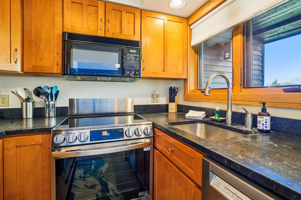 Bright kitchen featuring stainless appliances, ample cabinetry, and a window bringing in natural light.