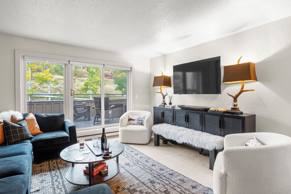 Cozy living room with comfortable seating, TV, fireplace and deck access.