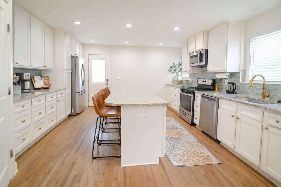 Chef’s kitchen with granite counters, stainless appliances, and island ba