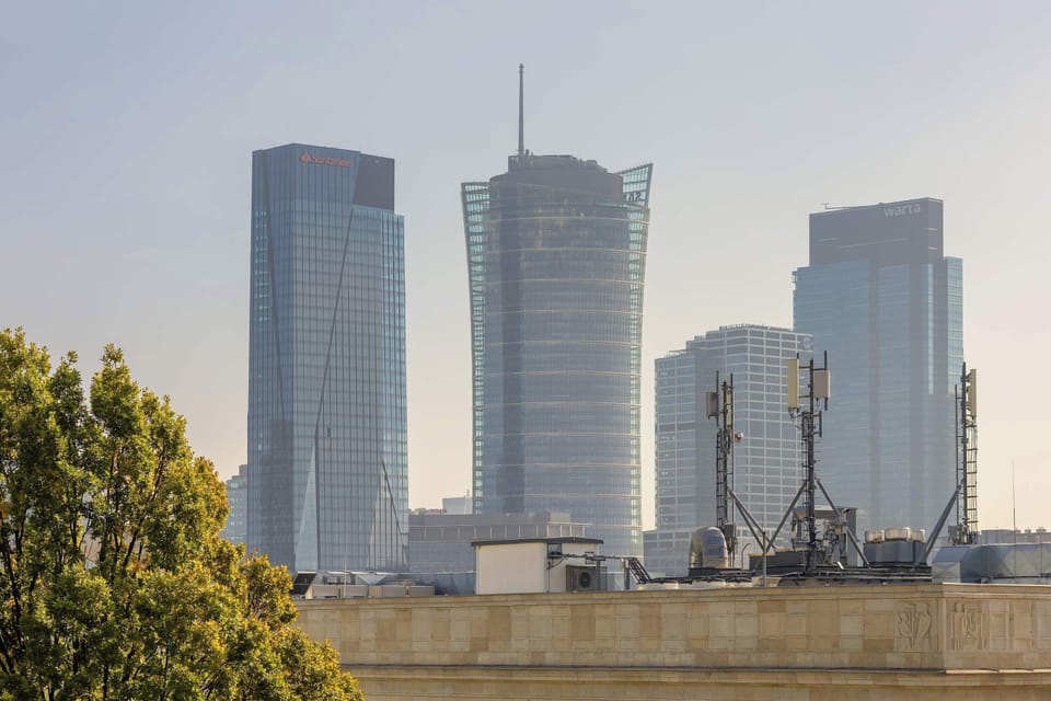 A view of tall modern office buildings with glass facades under a clear sky. The sleek skyline conveys a sense of business and progress.