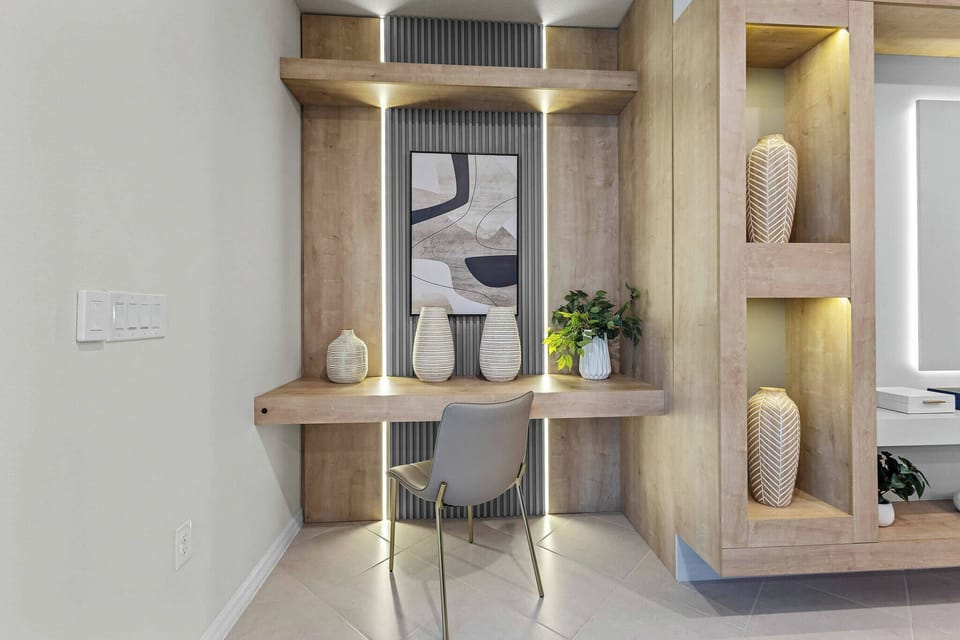 This stylish workspace features a sleek wooden desk and modern chair, complemented by soft lighting and contemporary decor. Fresh greenery and elegant vases create a warm, inviting atmosphere perfect for guests to be productive.