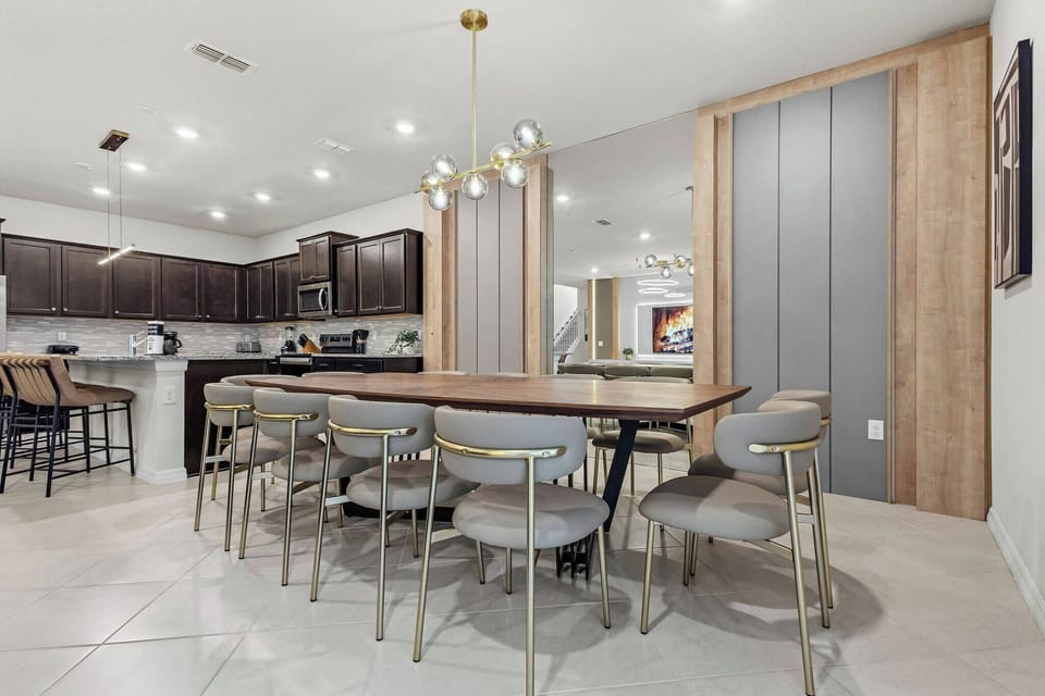 Join us at the spacious dining table, where modern chairs blend with rich cabinetry in the open kitchen. The stylish light fixture brings warmth, creating the perfect setting for shared meals and joyful laughter.