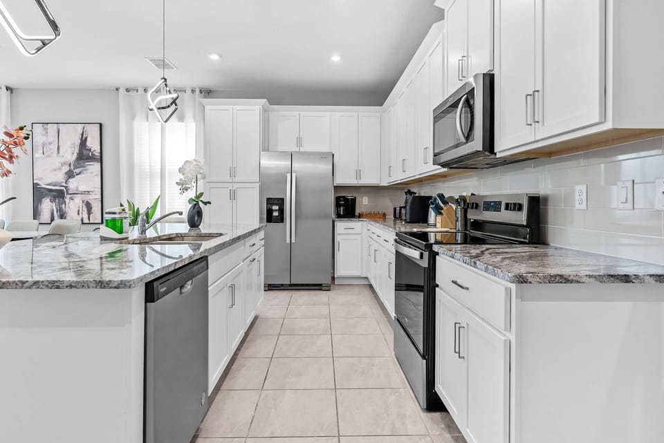 Welcome to a bright kitchen with sleek white cabinetry and elegant gray countertops, where modern stainless steel appliances and abundant natural light create a stylish, inviting space for all your cooking adventures.