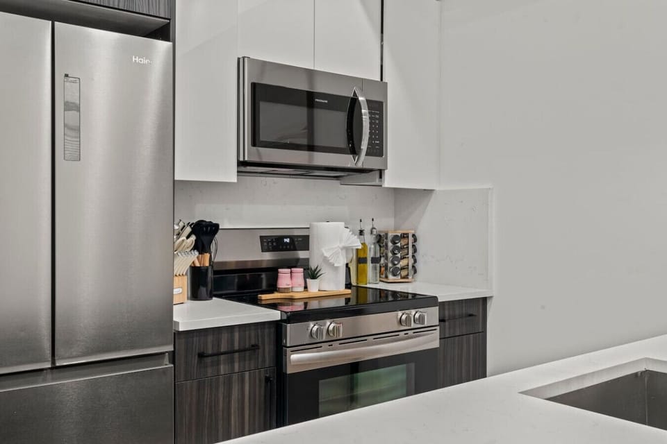 Modern kitchen with stainless steel fridge, stove, microwave, oven, utensils, knifes, spices, and more.