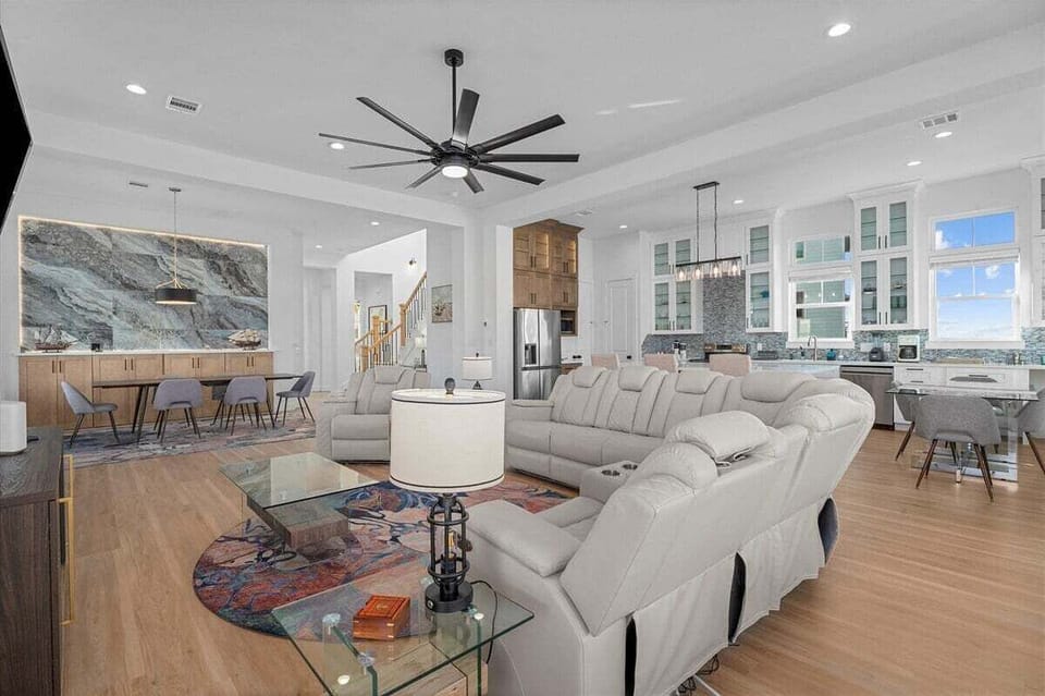 Large open living area with modern coastal furnishings and seamless flow into dining and kitchen spaces.