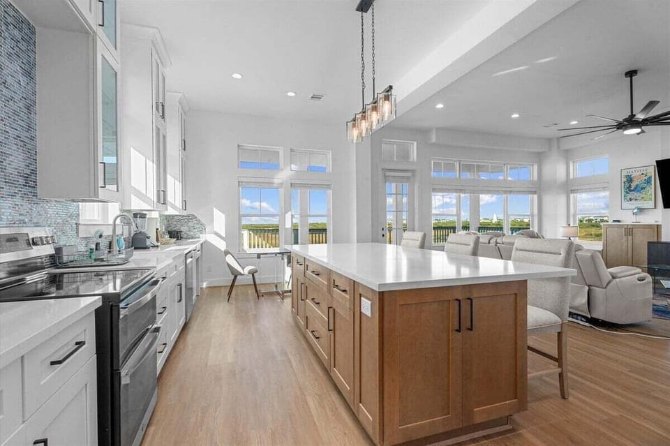 Open kitchen and island with seating overlooking the living area and large windows with marsh views.