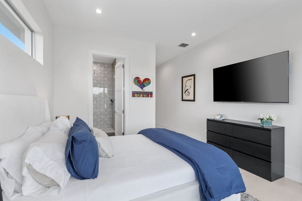 A soft, airy bedroom with cozy bedding and an easy flow into the modern bath gives guests another comfortable suite-style retreat.