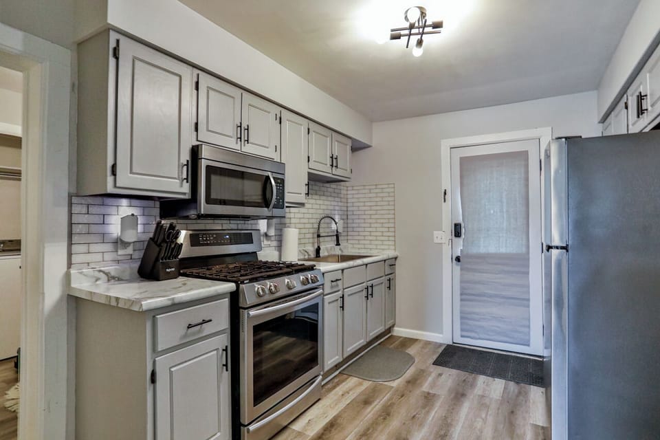 Updated kitchen with modern finishes, featuring stainless steel appliances, subway tile backsplash, and warm wood-style flooring.