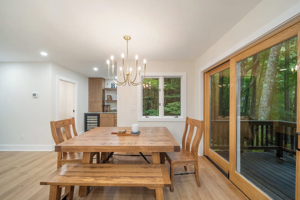 Dining Area with Beautiful Wood Table, Chairs and Benches next to Sliding Doors to the Deck