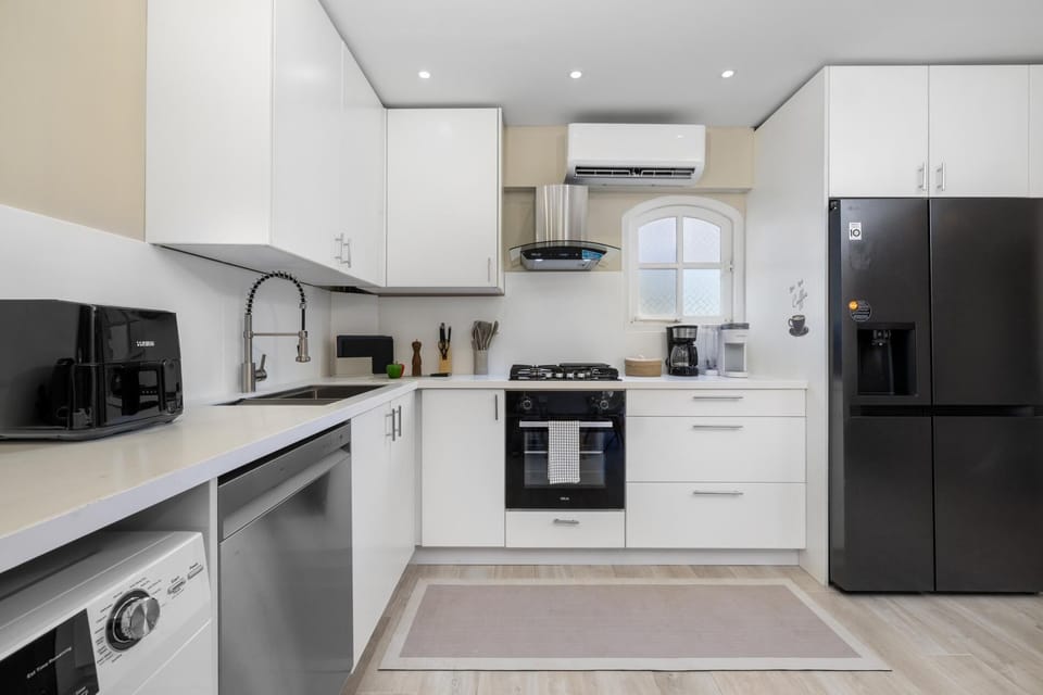 Cook and dine with ease in a fully equipped kitchen complete with modern appliances, cookware, and plenty of storage. The nearby dining table invites you to gather, share meals, and enjoy each moment together.