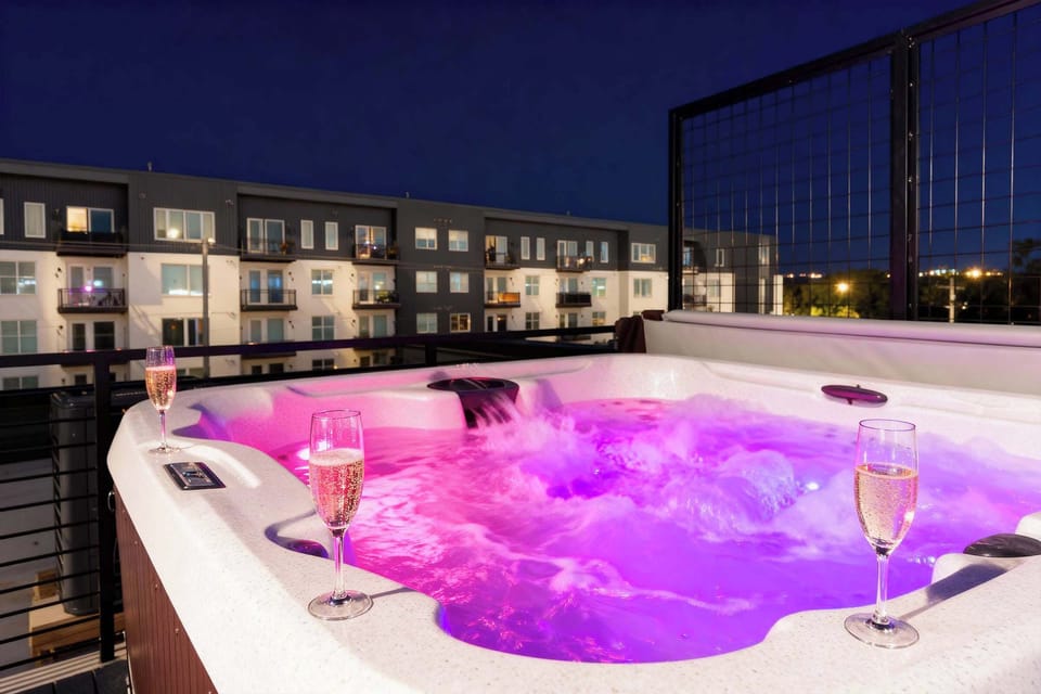 Pink and purple LED glow, champagne glasses ready, hot tub calling. Soak while the city glimmers behind you and book your group getaway with Misfit Homes