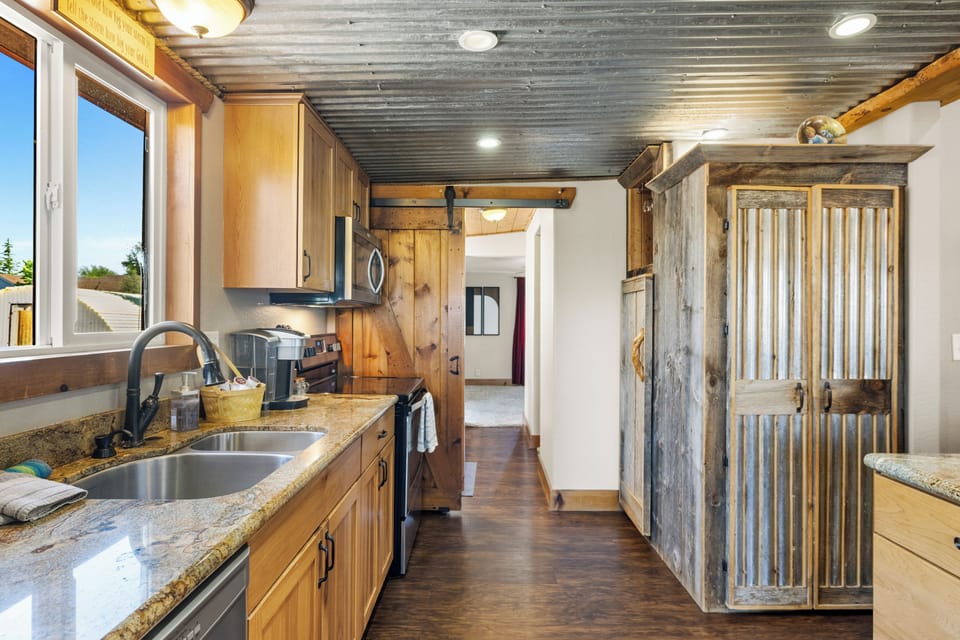 This rustic kitchen in home #1 features warm wood cabinetry, granite countertops, stainless steel appliances, and charming barn door accents for a cozy farmhouse feel.