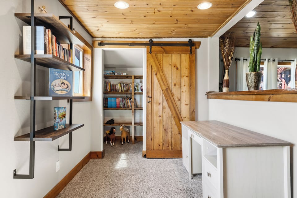 This cozy nook in home #1 doubles as a dedicated work or play area, complete with a desk, bookshelves, and charming barn-style touches.