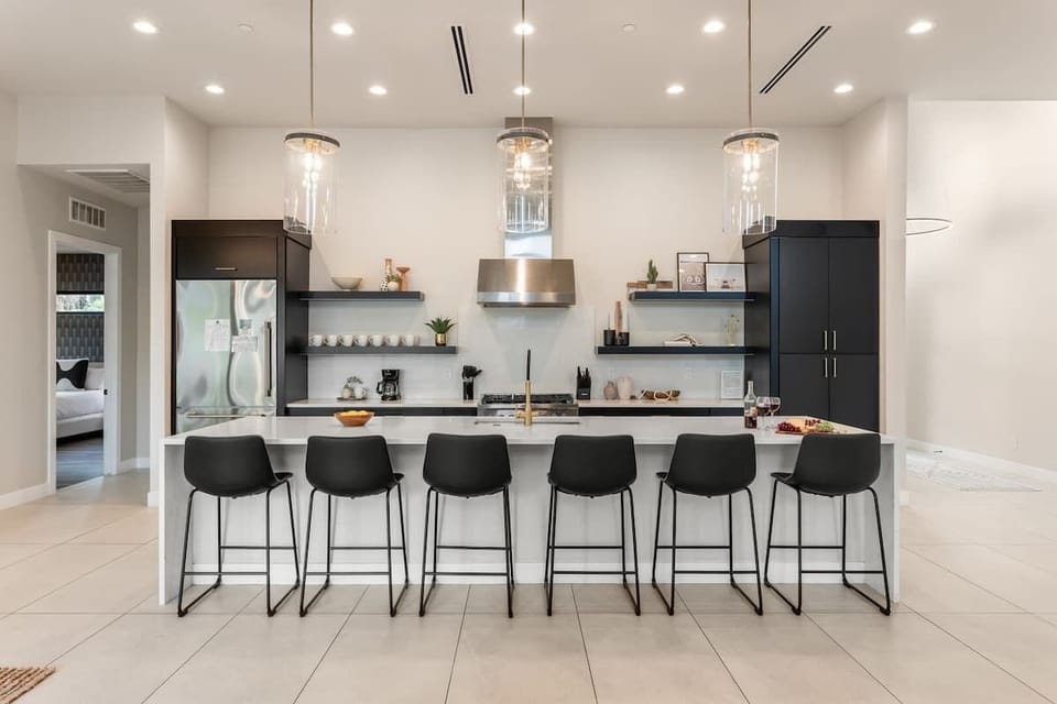 Large open-concept kitchen with brand new stainless steel appliances, quartz counter tops, large island with breakfast bar seating, and designer decor.