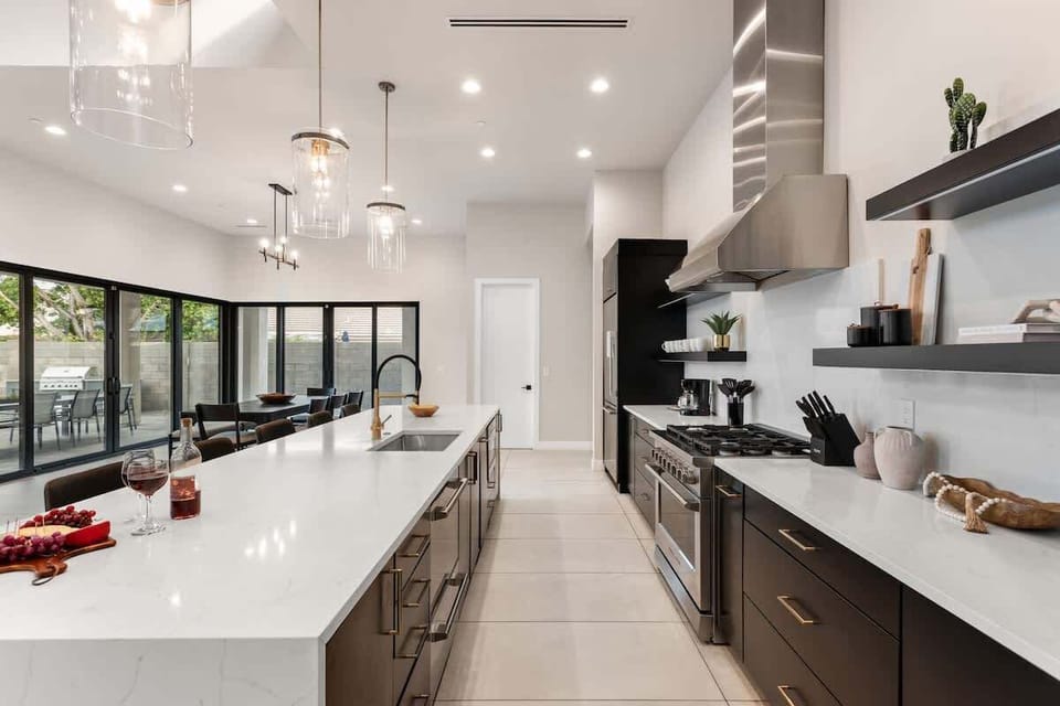 Large open-concept kitchen with brand new stainless steel appliances, quartz counter tops, large island with breakfast bar seating, and designer decor.