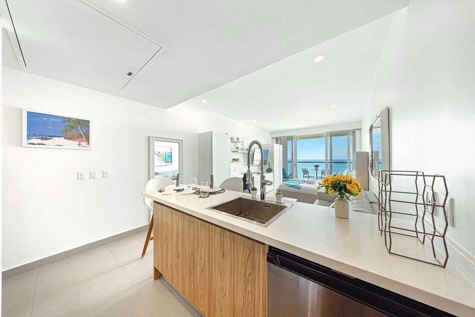 Enjoy cooking with a view—your sleek, open kitchen flows seamlessly into the living space, where floor-to-ceiling windows frame sparkling ocean vistas and flood your retreat with natural light.