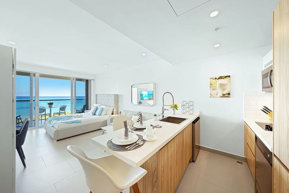 Step into your light-filled beachfront studio where the kitchen flows into your sleeping area and stunning ocean views greet you through floor-to-ceiling glass.