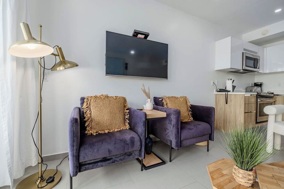 Sink into plush purple chairs while watching your favorite shows on the wall-mounted TV in this stylish open-plan space.