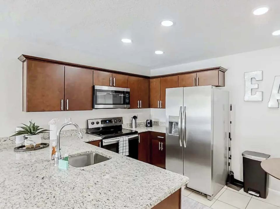 Sleek modern kitchen featuring stainless-steel appliances, granite countertops, and rich wood cabinetry. Fully equipped for cooking and entertaining, this bright space blends functionality with contemporary charm.
