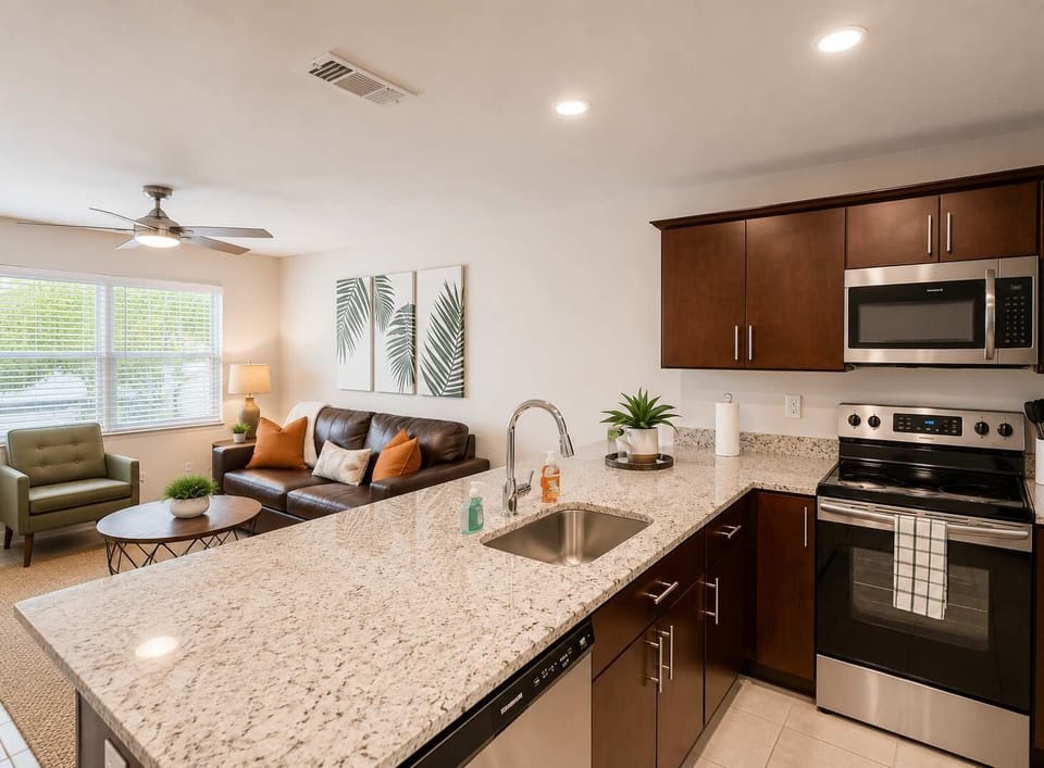 Modern kitchen with sleek granite counters, stainless-steel appliances, and rich wood cabinetry overlooking a bright, cozy living space. Perfect for cooking, entertaining, or relaxing in comfort and style.