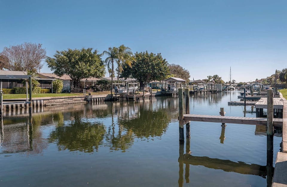 Peaceful canal view lined with charming homes and lush palms. Enjoy serene waterfront living, perfect for fishing, or simply soaking in the Florida sunshine from this tranquil setting.