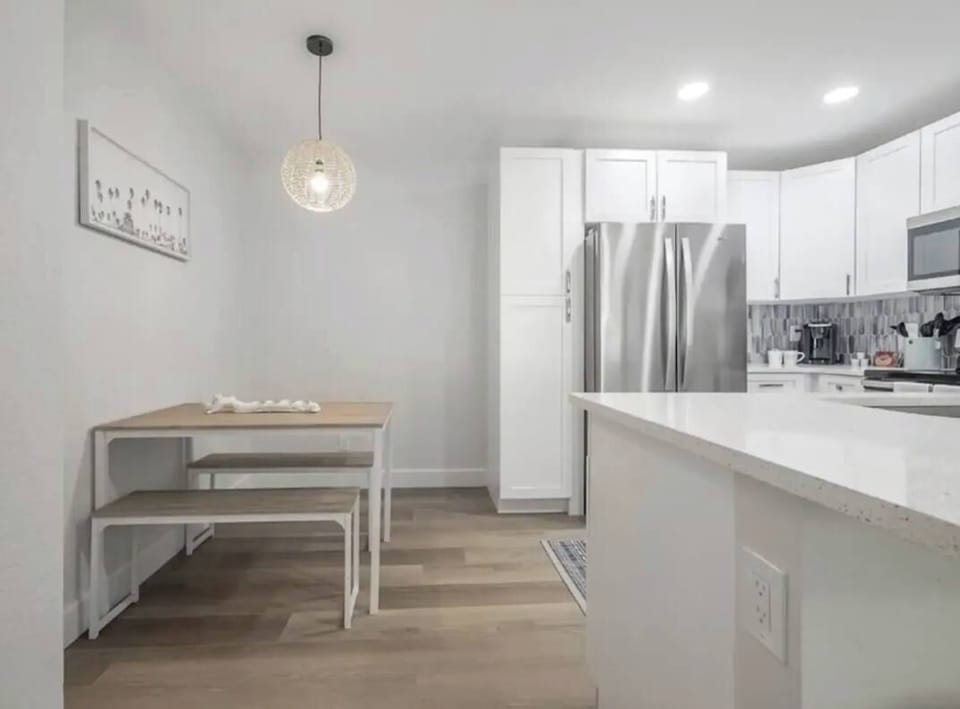 Charming dining nook with a modern wooden table and bench seating, illuminated by a stylish pendant light. Nestled beside the kitchen, it offers a cozy, contemporary space perfect for enjoying meals or morning coffee.