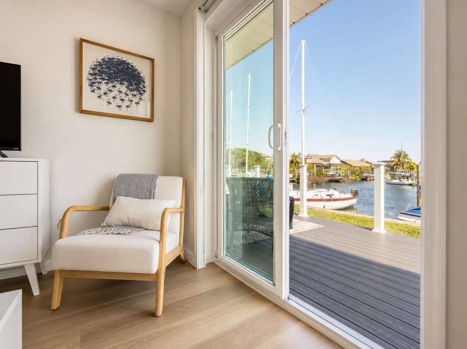 Peaceful waterfront view from a cozy sitting nook with modern décor and sliding glass doors leading to the deck. Perfect for morning coffee or evening sunsets overlooking the canal and passing boats.